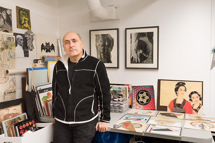 Carl George standing in front of a collection or artworks, photographs and records.